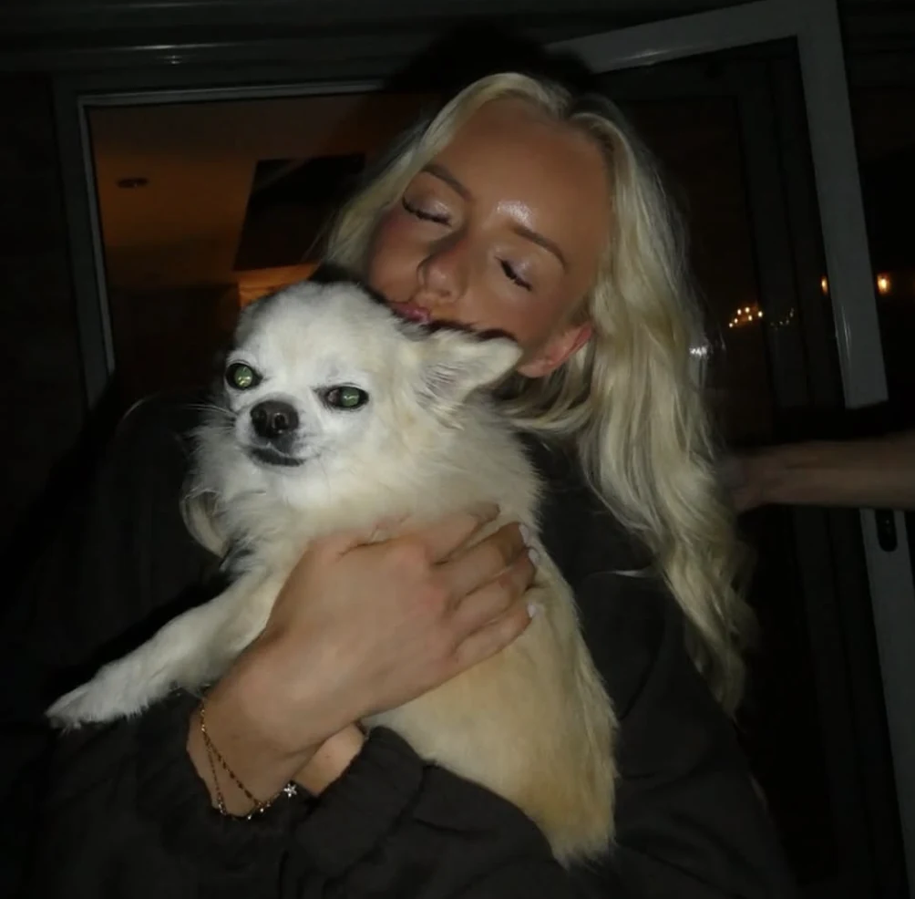 Ellie cuddling her little cream dog at home